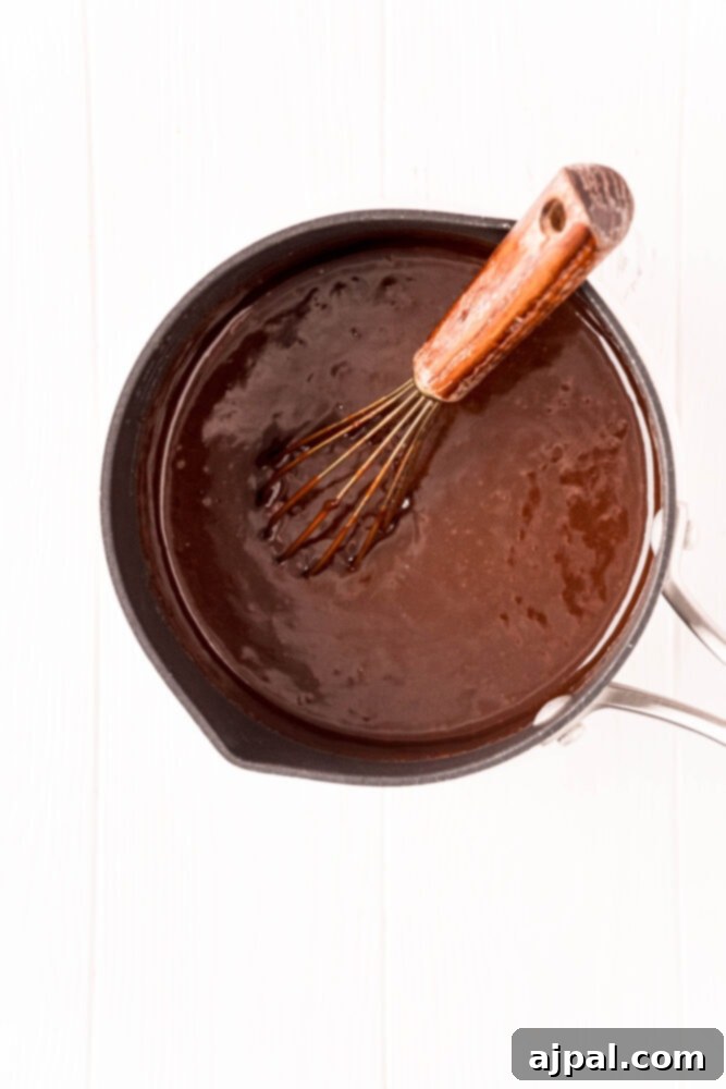 Cocoa powder and butter melting in a saucepan, being whisked gently