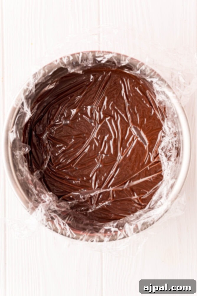 Melted chocolate in a bowl covered with plastic wrap, chilling in the refrigerator