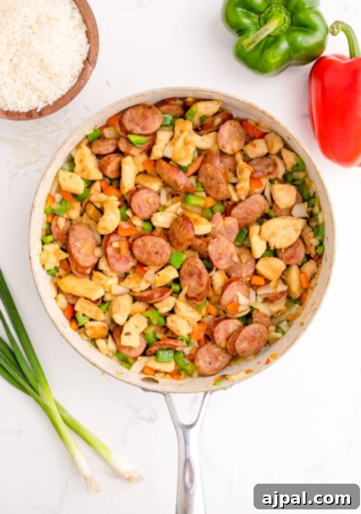 picture of chicken and sausage and vegetables browning in a pan