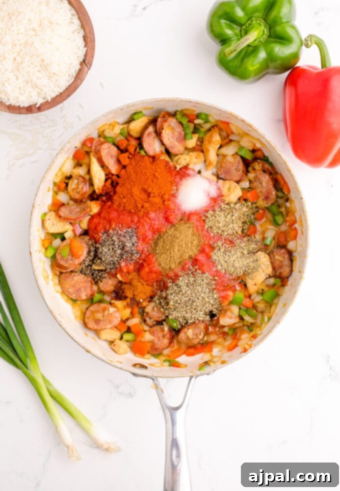 picture of chicken, vegetables, and sausage browning in a pan with cajun spices
