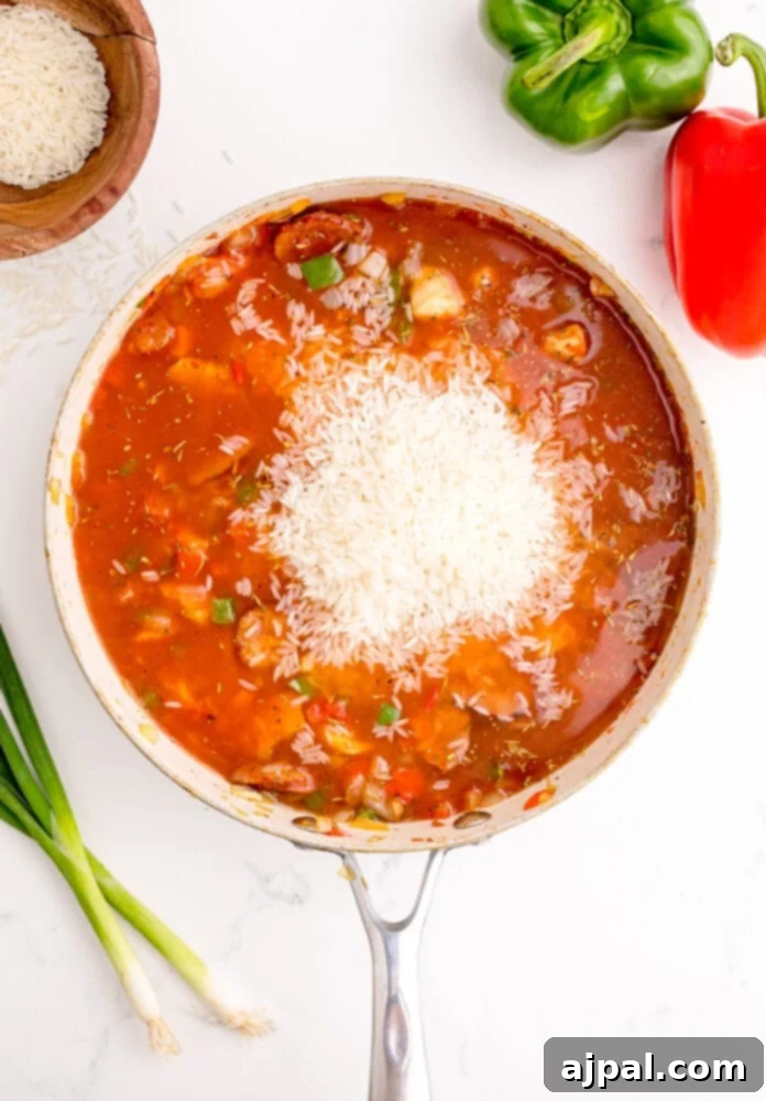 picture of jambalaya base simmering in a pan with rice on top