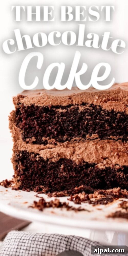 Decadent Chocolate Perfection 7 A slice of homemade chocolate cake with a rich, moist texture, topped with creamy frosting and a hint of a crumbly topping, presented on a white plate with a silver fork.