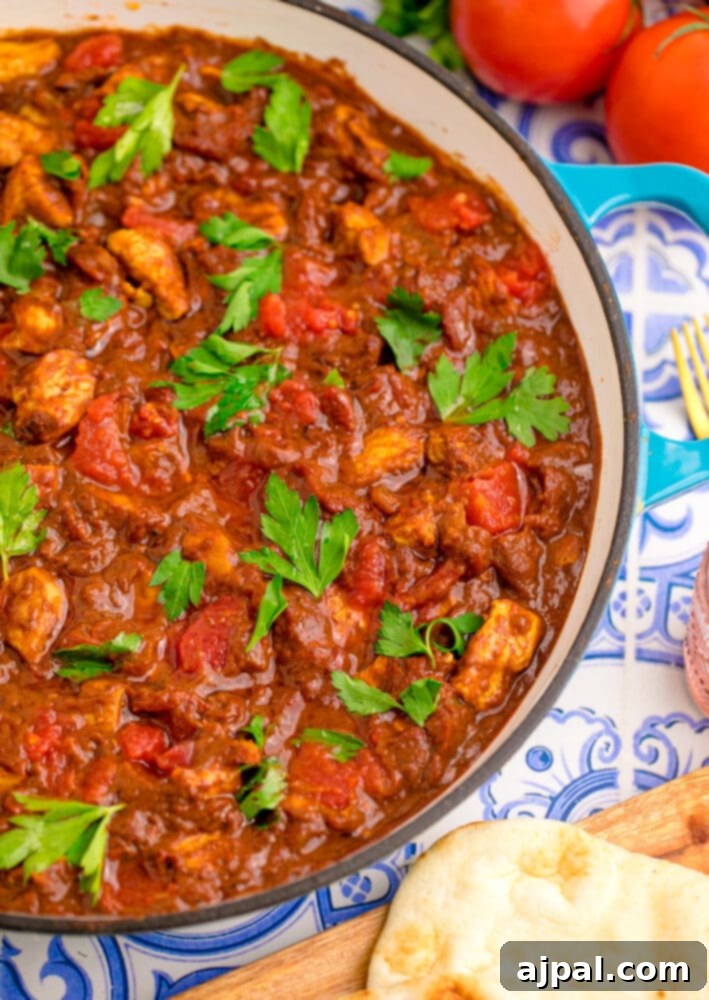 A hearty serving of Chicken Madras Curry presented beautifully in a pan, invitingly ready to be enjoyed.