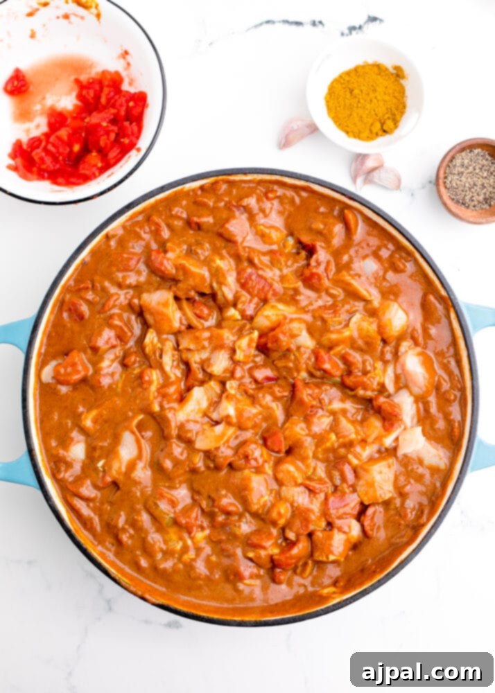 Bite-sized chicken pieces simmering in a rich, creamy Madras curry sauce, absorbing all the aromatic flavors.