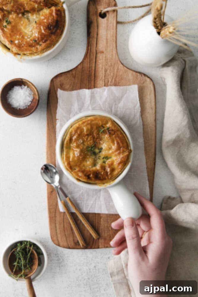 A perfectly golden-brown individual chicken pot pie in a white ramekin, ready to be enjoyed.