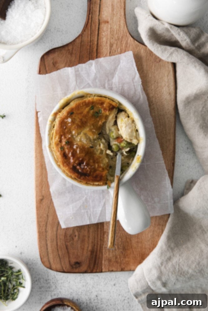 A beautifully baked individual chicken pot pie in a white ramekin, showcasing its golden crust and comforting appeal.