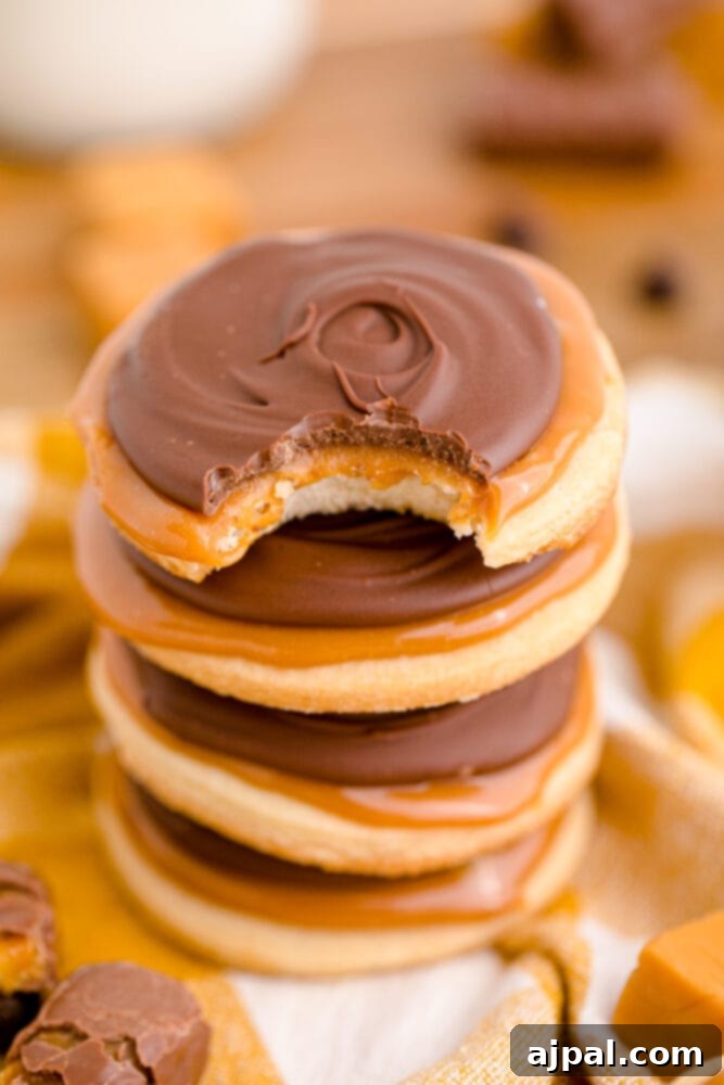 picture of a stack of twix cookies on a yellow towel, highlighting their golden shortbread base, gooey caramel, and chocolate topping.