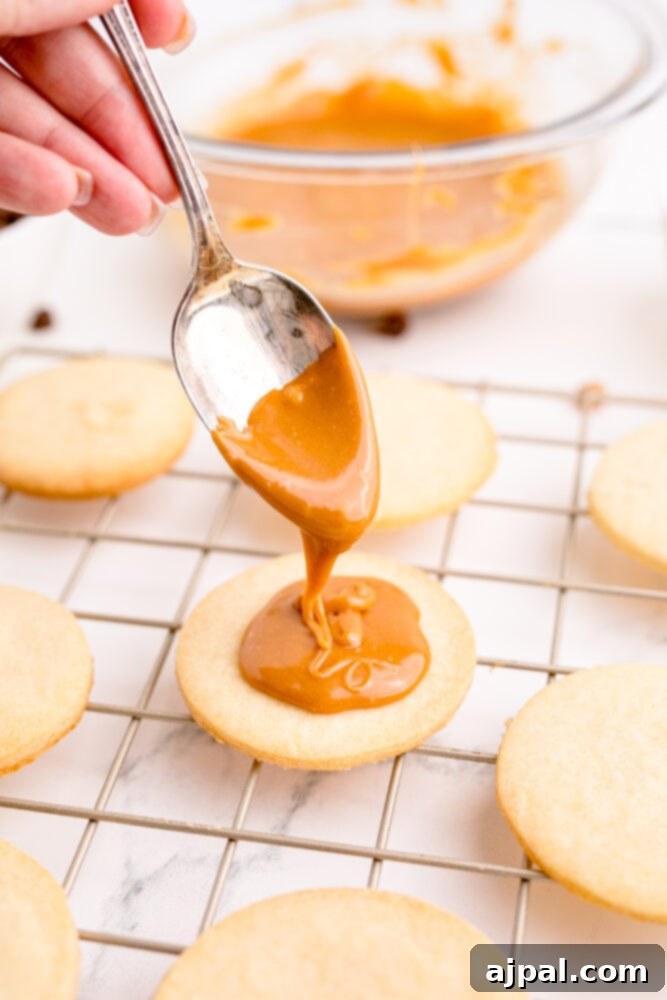 picture of a spoon adding caramel onto shortbread cookie, demonstrating the layering process.
