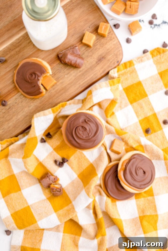 picture of a stack of twix cookies, next to a glass of milk on a checkered tablecloth, ready to be enjoyed.
