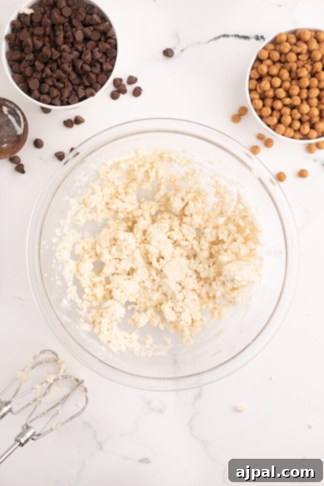 picture of cookie dough in a bowl being blended with a hand mixer, showing the creamy texture developing.