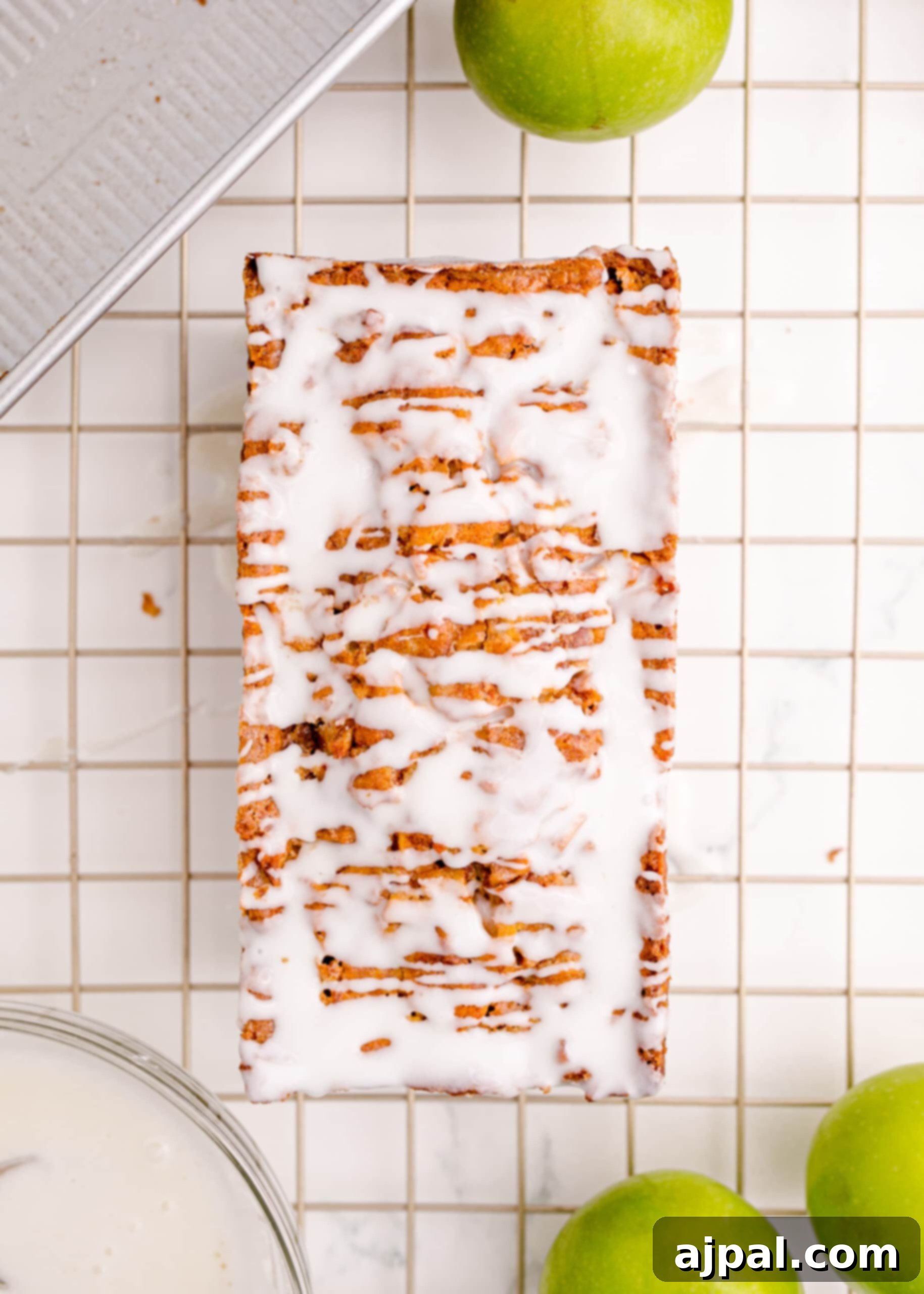 Picture of a freshly baked, iced apple fritter bread cooling on a wire rack, ready for serving.