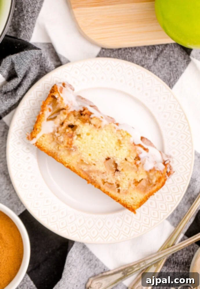 A perfectly sweet slice of apple cake on a pristine white plate, showcasing its layers and glaze.