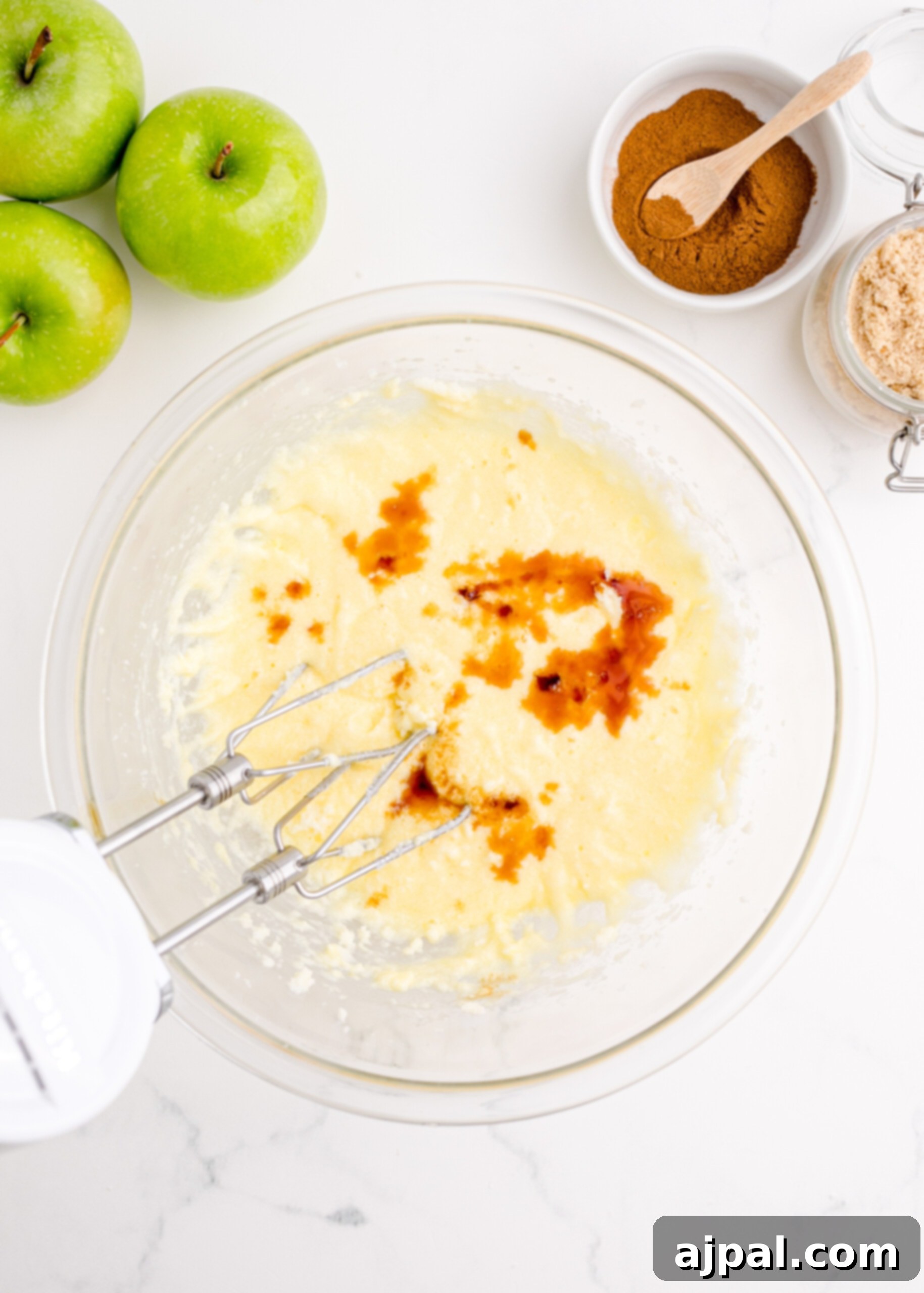 A bowl of batter with apples and cinnamon, demonstrating the initial steps of an easy apple fritter bread recipe.
