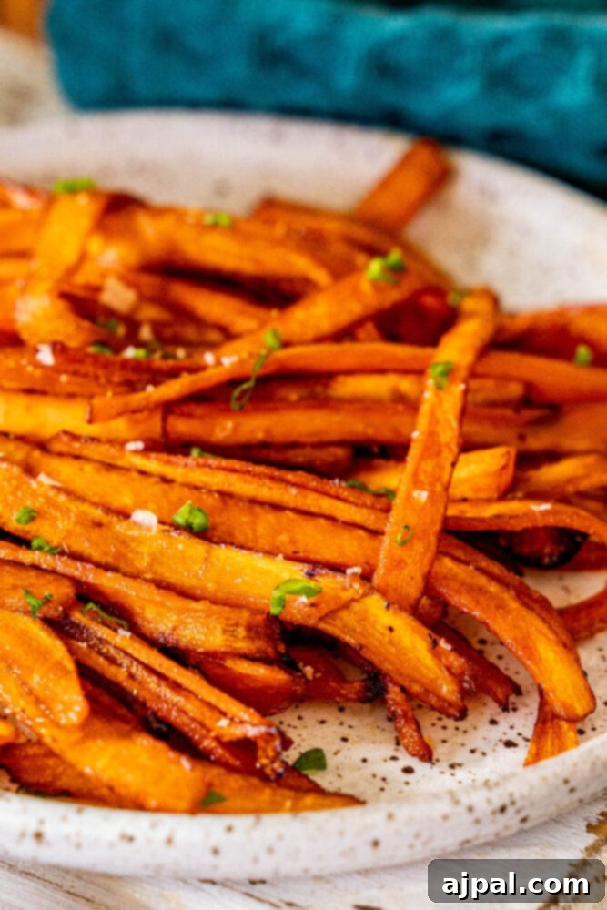 Crispy vegan carrot bacon strips arranged on a plate with fresh chives and a sprinkle of salt, ready to be enjoyed as a savory snack or breakfast side.