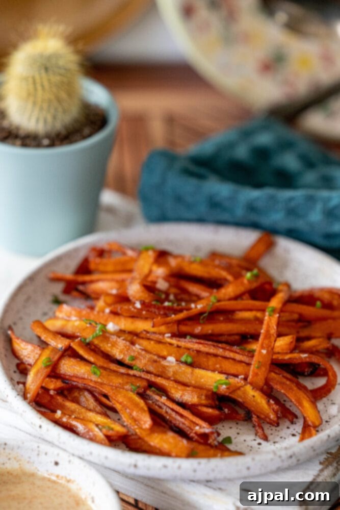 A delightful plate showcasing crispy vegan carrot bacon alongside a side of sweet potato fries, accented by a small decorative cactus for a charming presentation.
