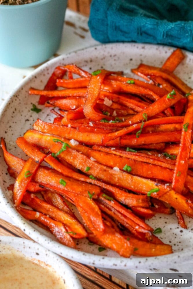 A beautiful plate featuring freshly baked vegan carrot bacon strips next to a small bowl of dipping sauce, highlighting their crispy texture and savory appearance.
