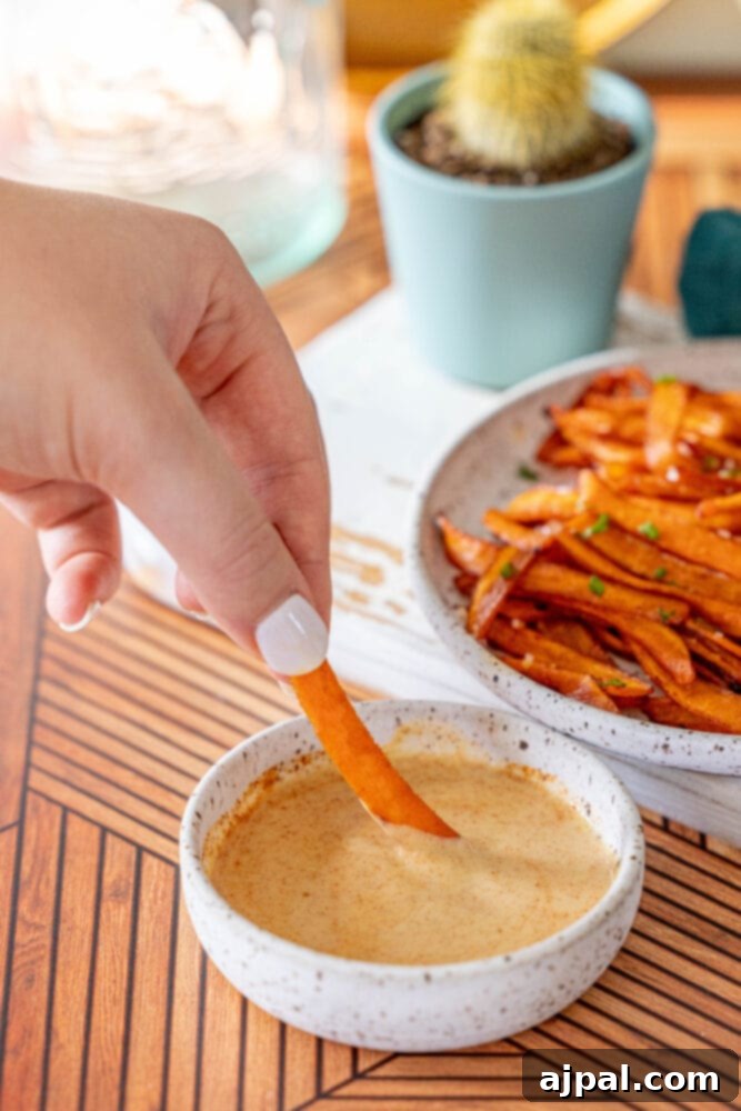 A person enjoying a plate of crispy vegan carrot bacon alongside golden sweet potato fries, showcasing a delightful plant-based meal.