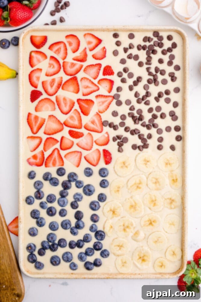 A top-down view of sheet pan pancake batter, evenly spread in a baking sheet, ready for toppings and the oven.