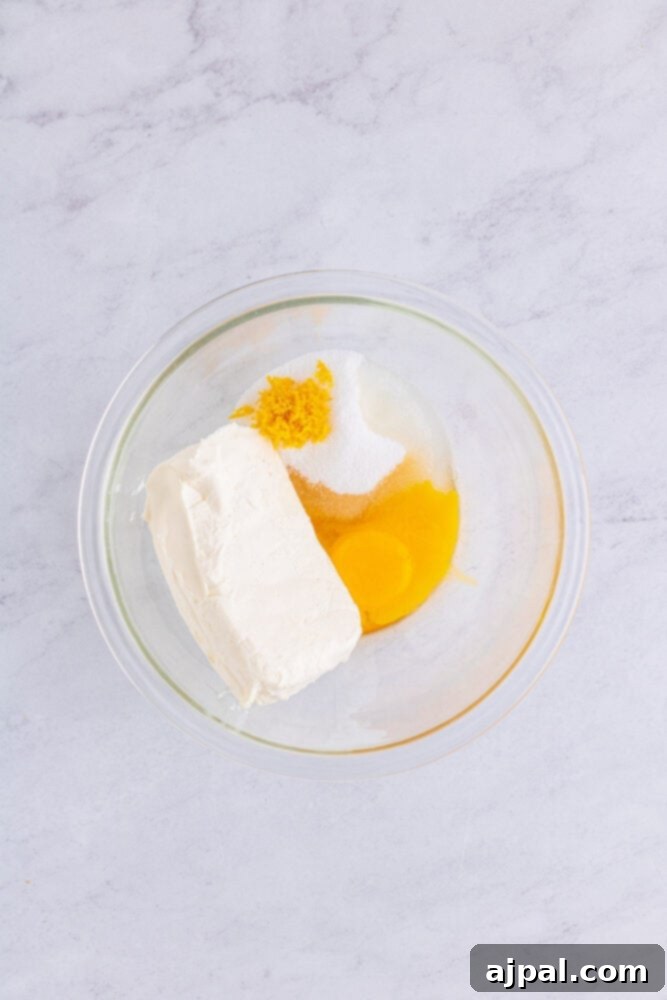 Danish ingredients, including cream cheese, sugar, and an egg yolk, mixed together in a bowl.