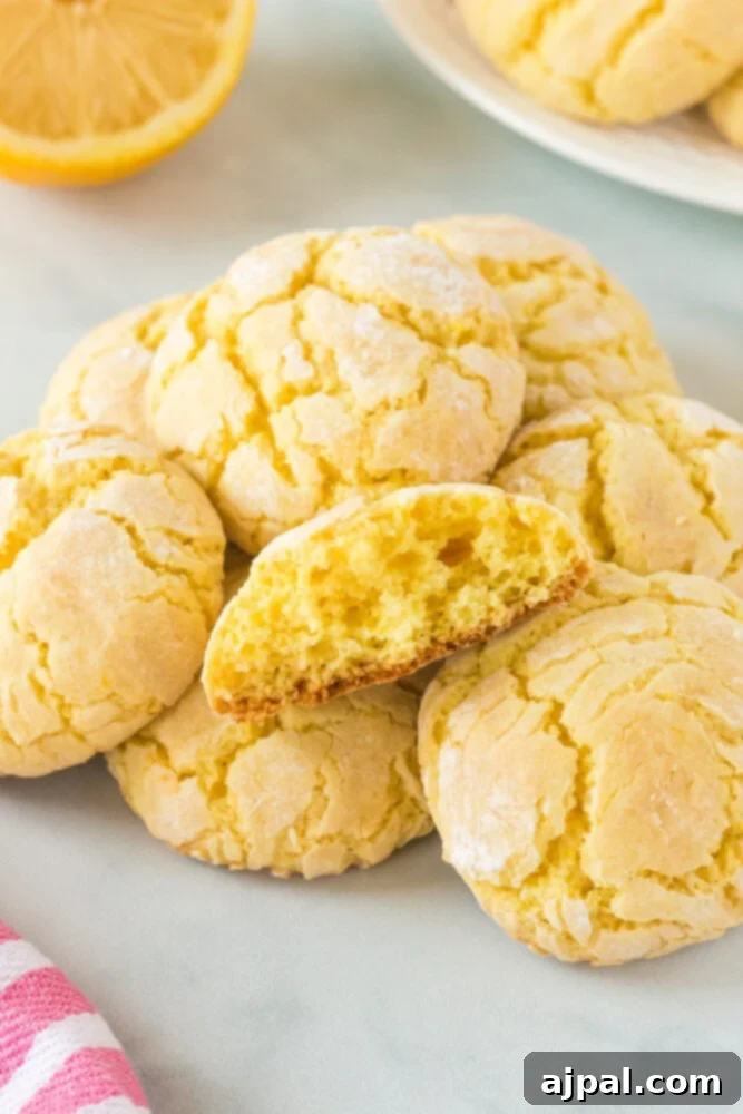 A close-up shot of freshly baked lemon crinkle cookies, still warm on a cooling rack, highlighting their powdered sugar coating and soft texture.