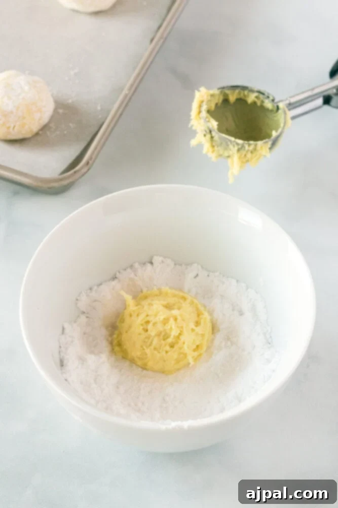 picture of cookie dough being rolled in powdered sugar
