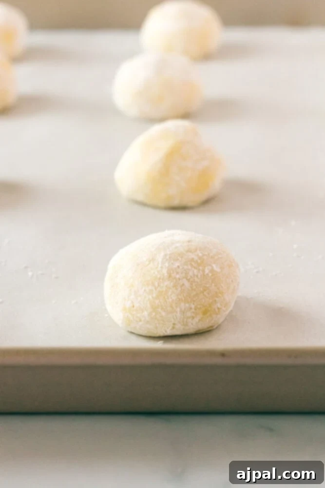 picture of cookie dough ball rolled in sugar on a baking sheet