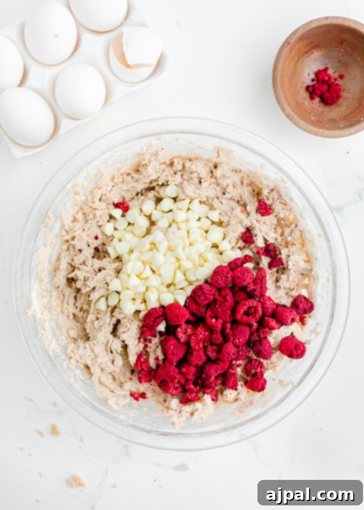 A mixing bowl filled with the combined wet ingredients for the cookies, including creamed butter and sugar, eggs, vanilla, and raspberry jam.