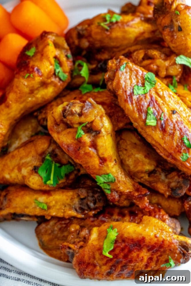 Smoky Tinga Slow Cooker Wings 2 A plate of juicy Slow Cooker Chicken Tinga Wings garnished with fresh parsley and carrots, with a slow cooker in the background.