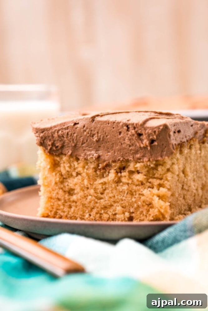 Ultimate Peanut Butter Cake 12 A rich slice of homemade peanut butter cake on a plate, accompanied by a refreshing glass of milk.