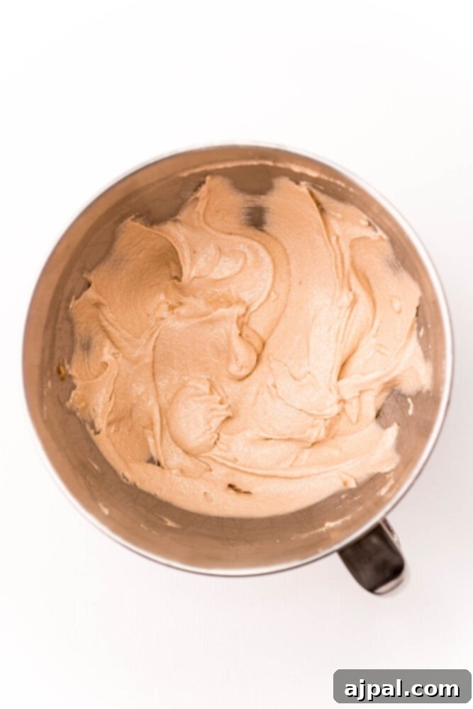 Ultimate Peanut Butter Cake 5 Close-up of cake batter being mixed in a bowl with an electric mixer, creating a smooth consistency.