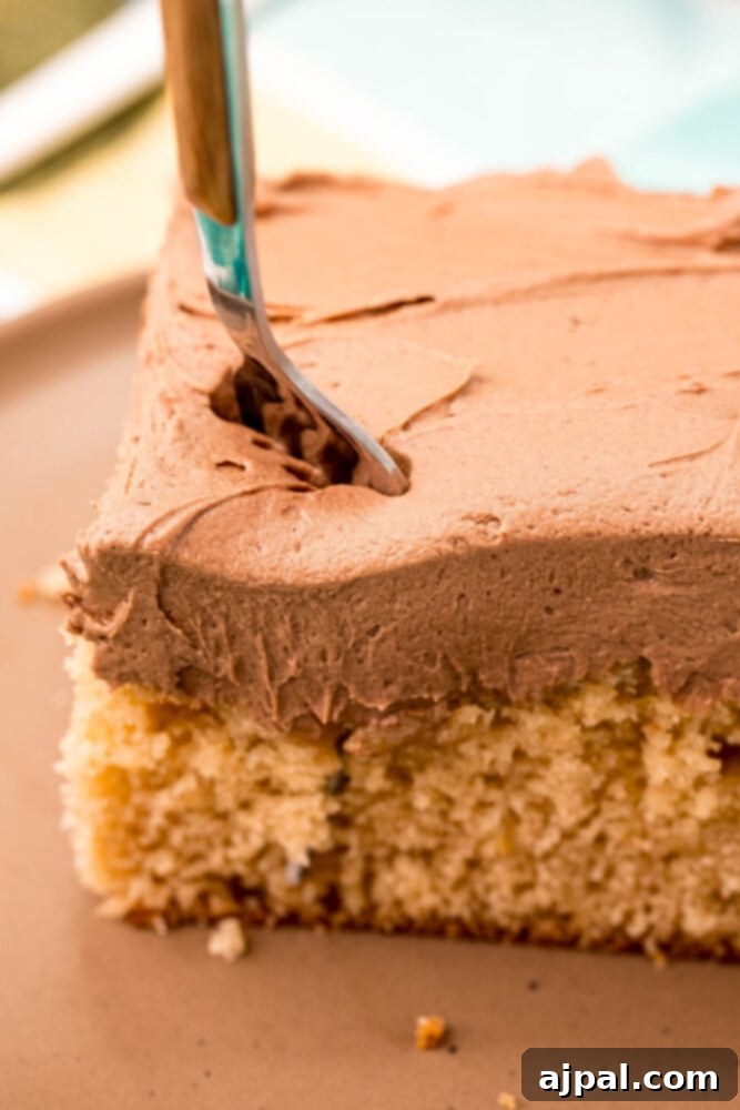 Ultimate Peanut Butter Cake 9 A perfect slice of peanut butter cake, beautifully frosted, served on a white plate with a fork.