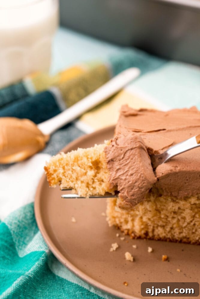 Ultimate Peanut Butter Cake 10 A slice of creamy peanut butter cake with a fork, presented elegantly on a plate.