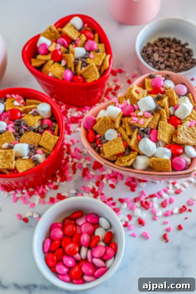 Valentine Smores Snack Mix 10 A large bowl of Valentine's S'mores Snack Mix, showcasing the appealing blend of crunchy cereal, soft marshmallows, colorful M&M's, and chocolate chips.