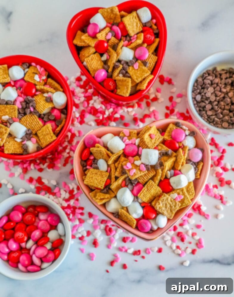 Valentine Smores Snack Mix 9 A beautifully presented bowl of Valentine's S'mores Snack Mix, featuring Golden Grahams, marshmallows, pink M&M's, and chocolate chips, with the festive red and pink colors prominent.