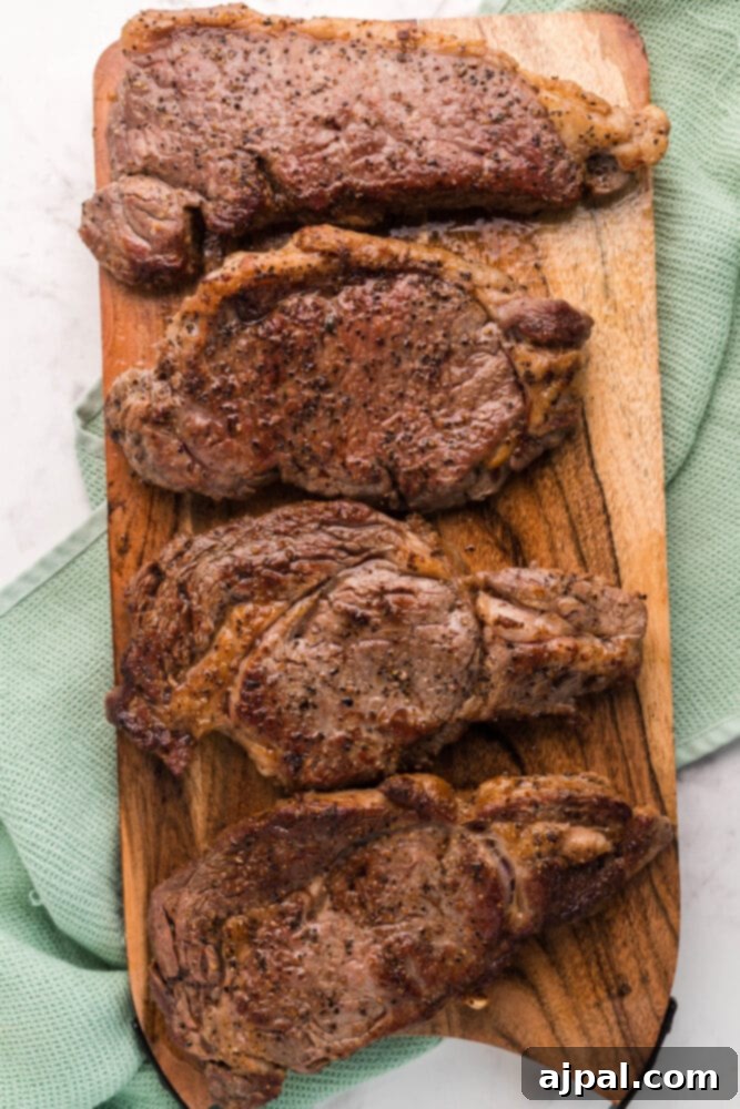 A freshly cooked New York Strip steak with a golden-brown crust, resting on a wooden cutting board.