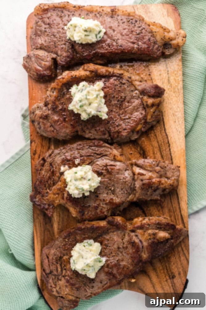 A cooked New York Strip steak topped with a generous scoop of blue cheese butter on a cutting board.