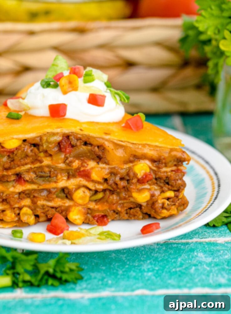 Hearty Taco Bake 11 A serving of layered taco pie on a white plate, garnished with fresh cilantro and a dollop of sour cream.