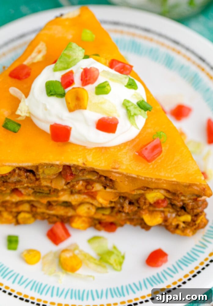Hearty Taco Bake 12 A vibrant slice of layered taco pie, garnished with fresh cilantro and a lime wedge, ready to be enjoyed.