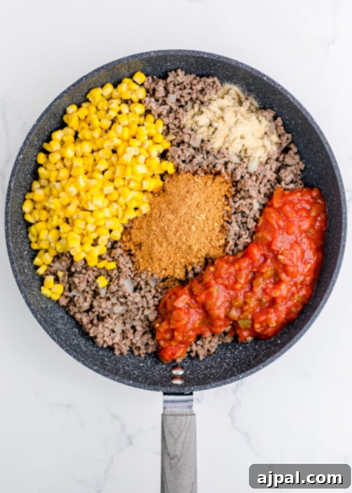 Hearty Taco Bake 6 The beef and onion mixture combined with corn, taco seasoning, and salsa, simmering in a pan.