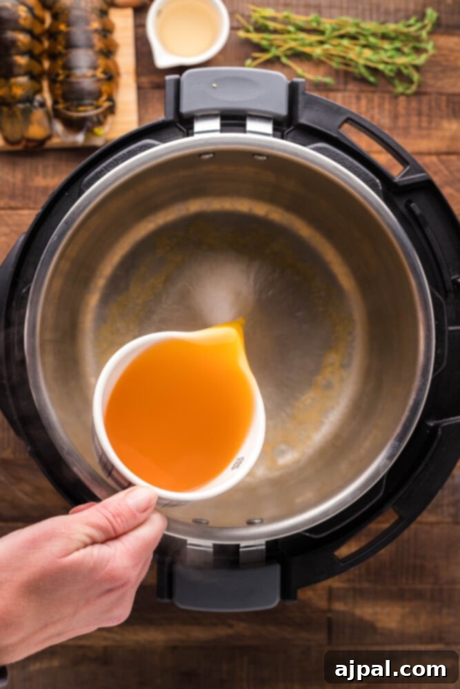 Instant Pot Creamy Lobster Brie Pasta 5 A stream of vegetable broth being poured into an Instant Pot, starting the cooking process for a delicious meal.