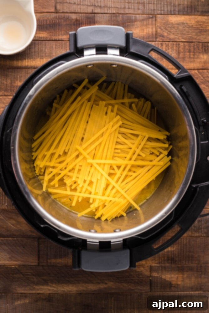 Instant Pot Creamy Lobster Brie Pasta 10 Uncooked fettuccine noodles neatly layered into the Instant Pot, ready to absorb the flavors of the broth.