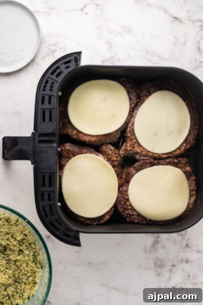 Melted provolone cheese glistening on top of an air-fried steak, creating a base for the Parmesan crust.