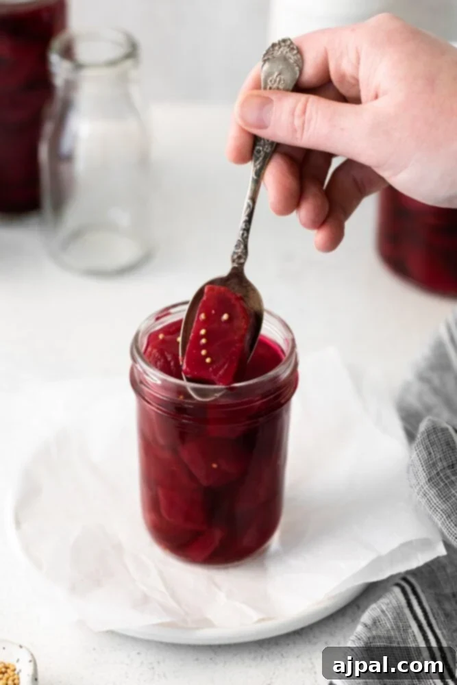 Jar of homemade quick pickled apple cider beets with a spoon, showcasing their vibrant color and fresh appeal.