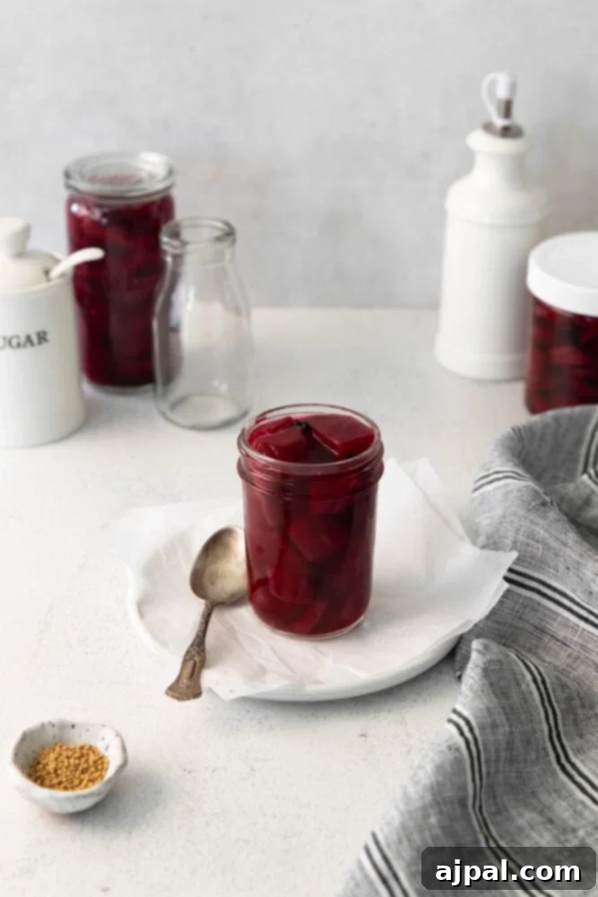 Pickled Apple Cider Beets in a jar on a white table, highlighting their vibrant color.