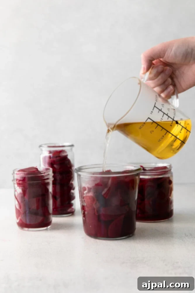 Pickling liquid being poured over beets in a jar.