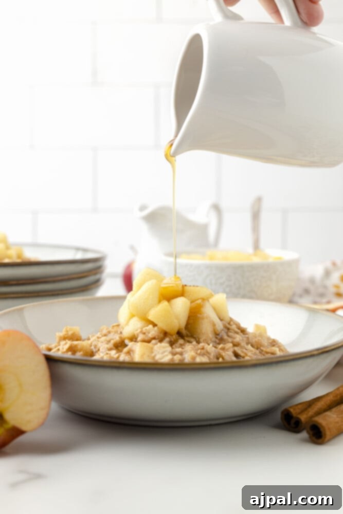 Syrup being poured over a bowl of apple cinnamon oatmeal, highlighting its inviting appeal.