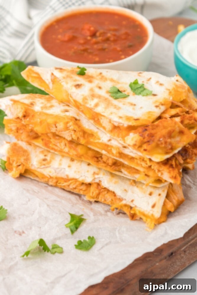 A stack of golden-brown chicken quesadillas, cut into triangles, on a wooden cutting board