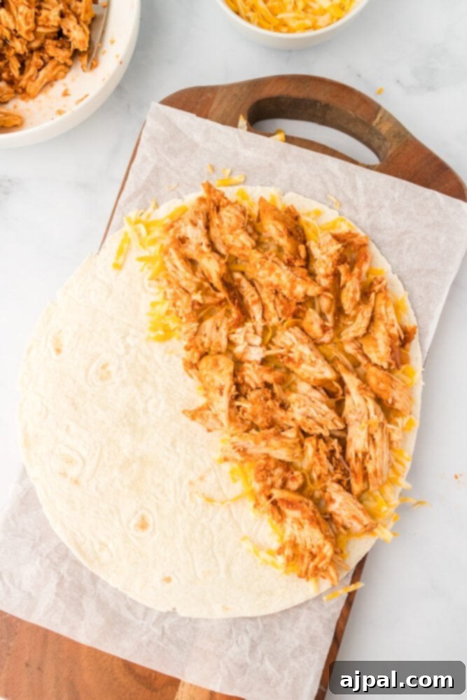 Layering shredded chicken onto a tortilla for a quesadilla