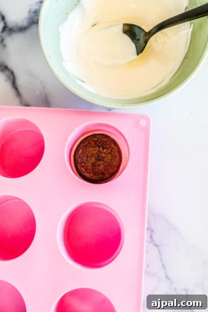 Picture of an Oreo being placed into a dipping mold filled with chocolate.