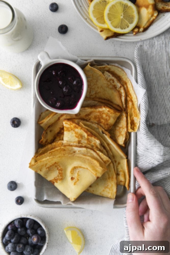 Another beautiful shot of lemon blueberry crepes on a dish with blueberry sauce, ready to be devoured.
